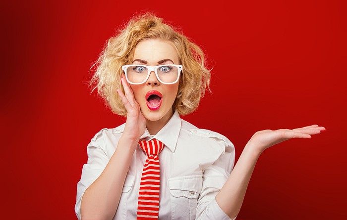 Surprised woman showing product, isolated on red background. Expression face